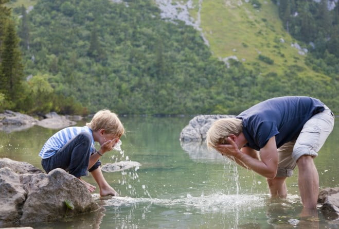 Far og sønn vasker ansiktet i fjellvann
